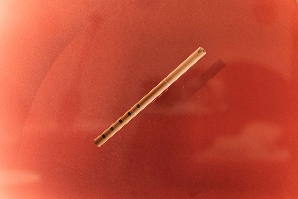 Flauta de madeira clara semelhante ao bambu, fina e alongada, com cinco orifícios no corpo para o dedilhado das notas.